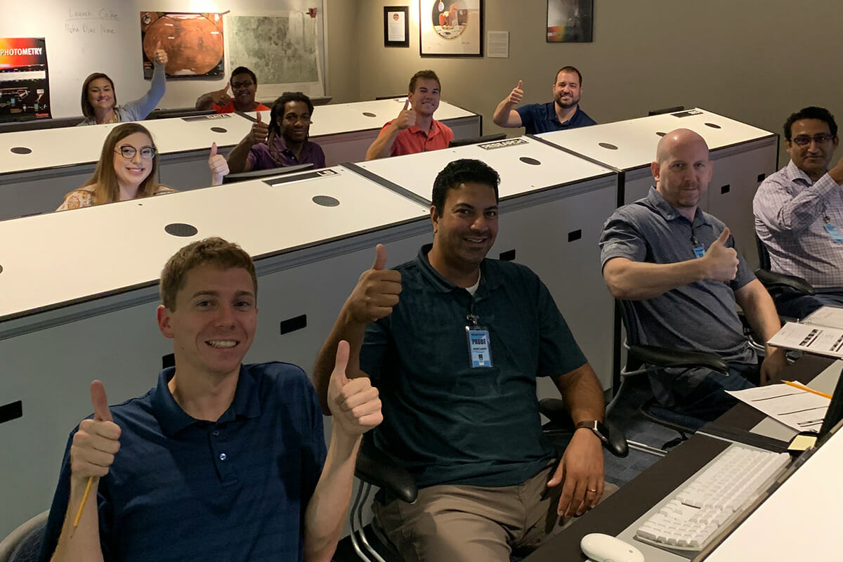 Group of people at mission computers giving thumbs up
