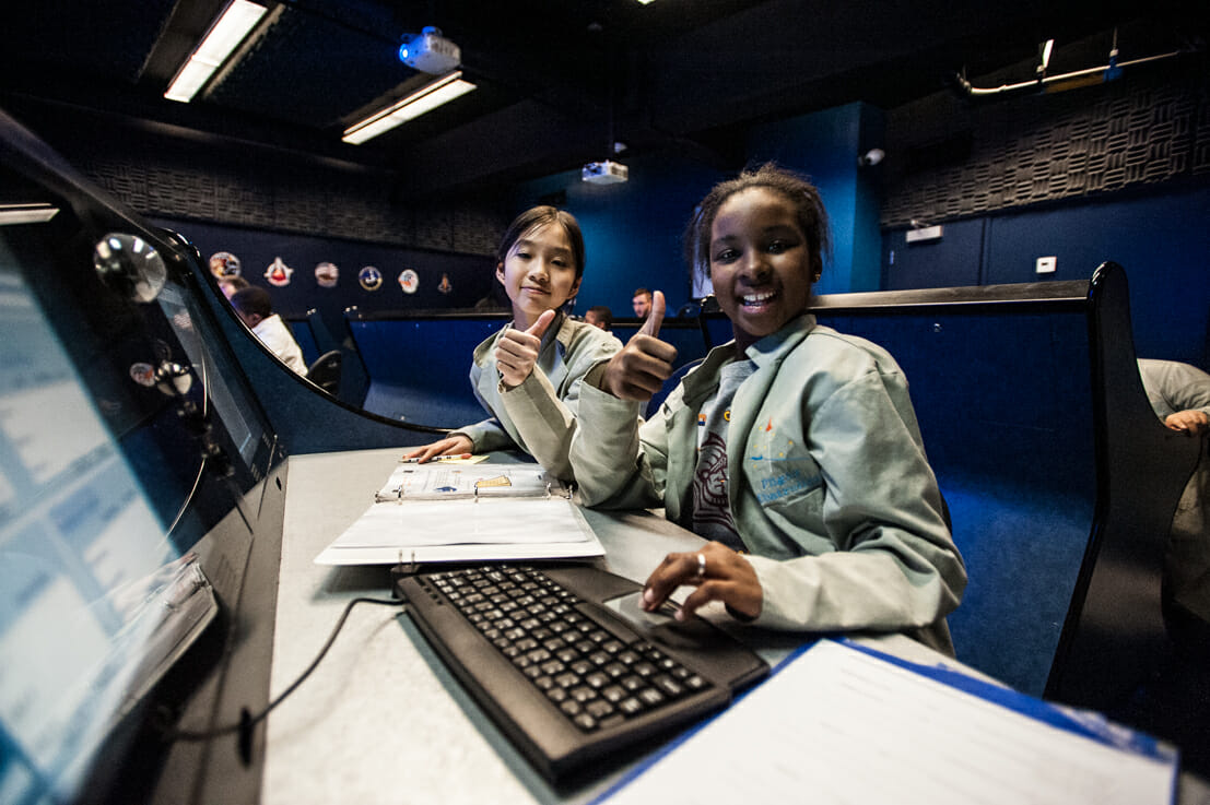 Two smiling children at mission computers