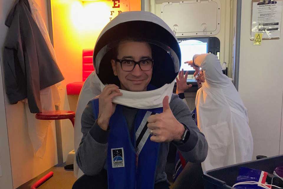 Teacher wearing space helmet and giving thumbs up